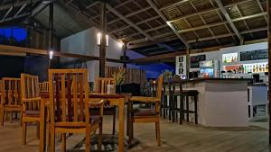 圣胡安Kawayan Holiday Resort的有桌椅和酒吧的餐厅