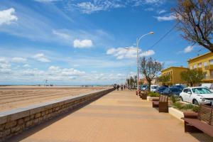 a sidewalk next to a beach with parked cars at Mobil-home chez MG in Sérignan