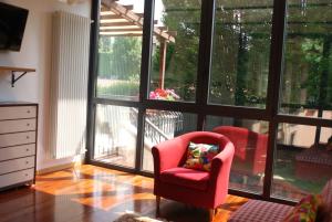 a living room with a red chair and large windows at Beija-Flor b&b in Verano Brianza