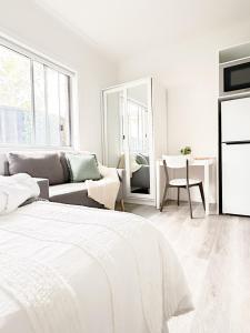 Un dormitorio blanco con una cama y un sofá. en Fortuna Laguna Coastal Studio Free Parking All INC, en Woonona