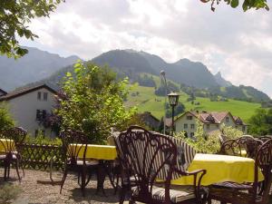 a table and chairs with a yellow table and mountains at Hotel Restaurant Belvedere in Weissbad