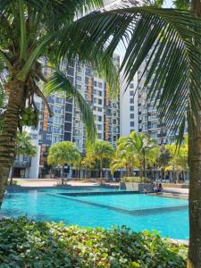 a swimming pool with palm trees and a large building at Timurbay Seafront Kuantan Beach D'Sunset Ombak Samudera in Kuantan