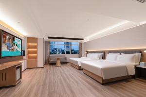 a hotel room with two beds and a flat screen tv at Echarm Hotel Haikou Friendship Sunshine City Wanlvyuan Branch in Haikou