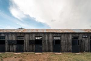 un vecchio fienile di legno con quattro finestre e un tetto arrugginito di Dwarsvlei Venue - Camping & Stables a Middelburg