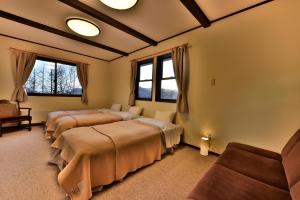ein Zimmer mit drei Betten, einer Couch und Fenstern in der Unterkunft Petit Hotel Kanan in Chino