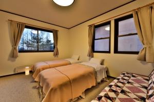 zwei Betten in einem Zimmer mit zwei Fenstern in der Unterkunft Petit Hotel Kanan in Chino