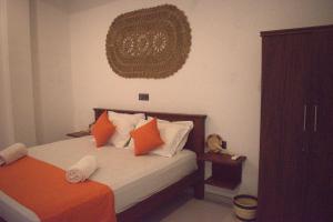 a bedroom with a bed with orange and white pillows at New View Hikkaduwa in Hikkaduwa