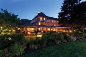 a hotel with tables and umbrellas in a garden at night at Ganter Hotel & Restaurant Mohren in Reichenau