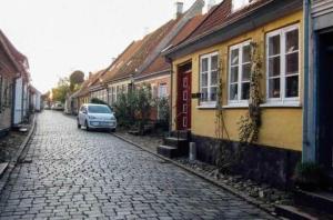 a car parked on a cobblestone street next to houses at AE297-Aeroskobing-Norregade-8 in Ærøskøbing