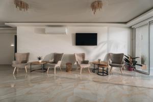 a room with chairs and tables and a flat screen tv at Golden Coast Suites in Kypseli