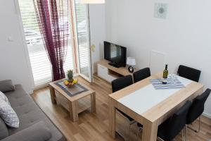 a living room with a couch and a table and a television at Apartment Gamma with hydromassage mini pool near Split in Žrnovnica