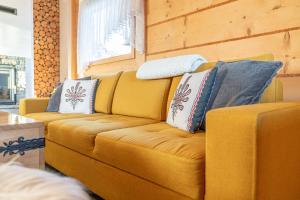 a yellow couch with pillows on it in a room at Osada Szaflary - jacuzzi na wyłączność dla każdego domku, ogólnodostępna sauna i plac zabaw w cenie in Szaflary +119 photos