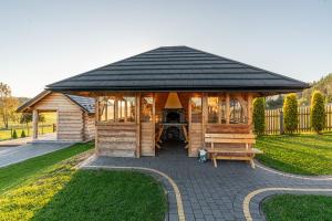 a large wooden gazebo with a black roof at Osada Szaflary - jacuzzi na wyłączność dla każdego domku, ogólnodostępna sauna i plac zabaw w cenie in Szaflary