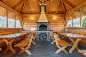 a dining room with wooden tables and a fireplace at Osada Szaflary - jacuzzi na wyłączność dla każdego domku, ogólnodostępna sauna i plac zabaw w cenie in Szaflary