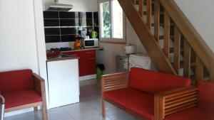 a kitchen with two red chairs and a staircase at Les Jardins Créoles in Cilaos