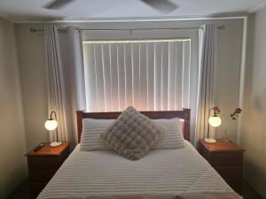 Un dormitorio con una cama con dos lámparas y una ventana. en Sunset Beach B&B, en Waggrakine