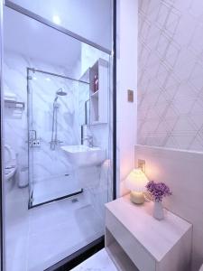 a white bathroom with a sink and a shower at The Luxury Hotel in Ho Chi Minh City