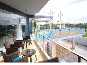 a balcony with chairs and tables and a swimming pool at Anna-Nava Pakkret Hotel in Nonthaburi