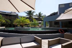 a resort pool with two chairs and an umbrella at Cozy Studio 2 in Trou aux Biches