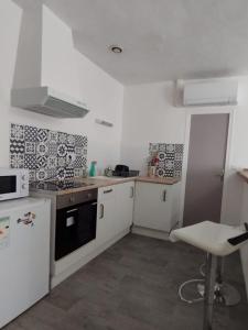 a kitchen with white cabinets and a black stove top oven at T2 Meublé, Équipé, Parfait pour Vos Séjours in Châteaumeillant