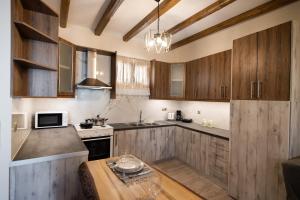 a kitchen with wooden cabinets and a wooden table at Stone Villa Hermione in Kariá