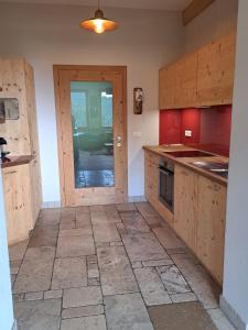 a large kitchen with wooden cabinets and a door at Baumannhof Hasental - adults only in Plazzoles
