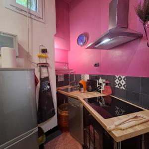 a pink kitchen with a sink and a refrigerator at Flat Liberty Turin center Porta Susa, reserved parking in Turin