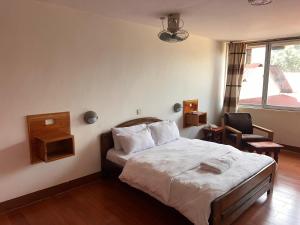 a bedroom with a bed and a chair and a window at Entebbe Fligh Motel in Entebbe