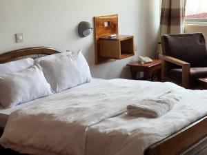 a bedroom with a bed with a chair and a phone at Entebbe Fligh Motel in Entebbe