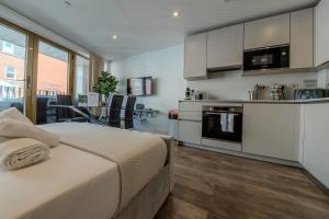 a bedroom with a large bed and a kitchen at Luxe London Retreat in London