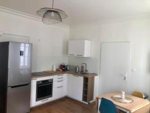a kitchen with a stainless steel refrigerator and a table at Appartement T2 - Centre-ville in Saint-Pourçain-sur-Sioule