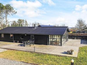 a black house with a deck and a table at 8 person holiday home in Hals-By Traum in Hals +30 photos
