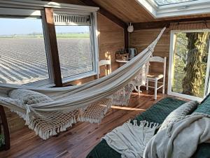 a hammock in a room with a view of a field at Sweet Treehouse in Westbeemster