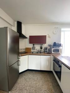 Una cocina con gabinetes blancos y un refrigerador de acero inoxidable. en Le Petit Noirda, en Audresselles