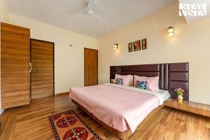 a bedroom with a large bed with pink pillows at Blisswood Villa by VEO - Part of StayVista in Trimbak