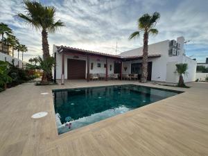 a swimming pool in front of a house with palm trees at Corona beach in Daimuz