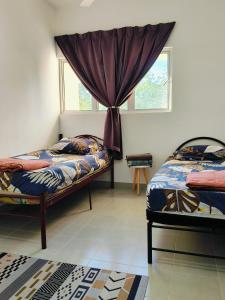 a bedroom with two beds and a window at Ryhan-Cha Homestay near Afamosa Waterpark in Gua Sai
