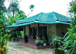 una pequeña casa amarilla con techo verde en Paddy Land, en Wayanad