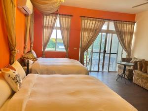 two beds in a room with orange walls and windows at Bellalia 貝拉利亞 花蓮民宿 in Hualien City