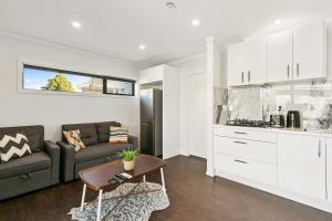 a kitchen and living room with a couch and a table at Modern 1 Bed Smart Flat in Upper Hutt with Full Kitchen, Parking - 5 minutes to Brewtown in Upper Hutt