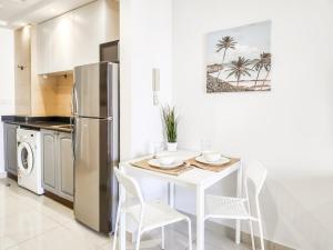 ラス・アル・ハイマにあるCozy Studio in Royal Breeze Al Hamraの白いテーブルと冷蔵庫のあるキッチン