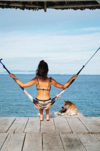 a woman in a bikini sitting in a hammock with a dog at Sanctum Una Una Eco Dive Resort in Pulau Unauna