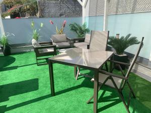 a table and chairs on a balcony with green grass at VILLA HELENA Crystal Apartment in Caniço