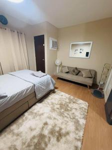 a bedroom with a bed and a couch at BRIA Flat Condo in Kauswagan