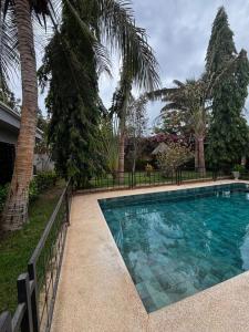 a swimming pool with palm trees and a fence at Modern villa with pool views in Ngaparou +22 photos