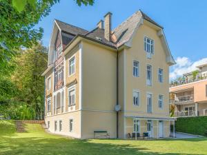 a large house with a grass yard in front of it at Stilvolle Gartenwohnung im Villenviertel Villachs in Villach