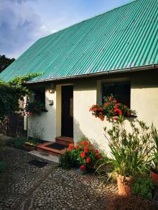 een wit huis met een groen dak en rode bloemen bij Lipowa 6 Łagów Lubuski in Łagów +24 foto's
