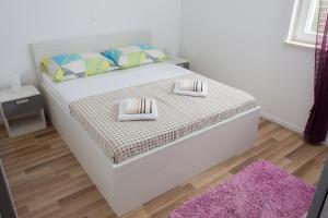 a white bed with two pillows and a purple rug at Apartment Gamma with hydromassage mini pool near Split in Žrnovnica +27 photos