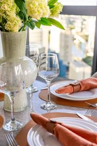 Una mesa con platos y vasos y un jarrón con flores. en Queen's Wharf 1B+Study, en Brisbane 15 fotos más