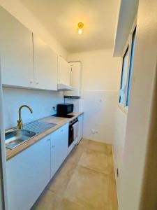 a white kitchen with a sink and a stove at Beach and Sun two minutes away in Nice